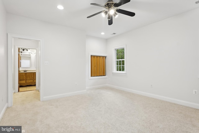 unfurnished bedroom featuring light carpet, ceiling fan, and ensuite bathroom