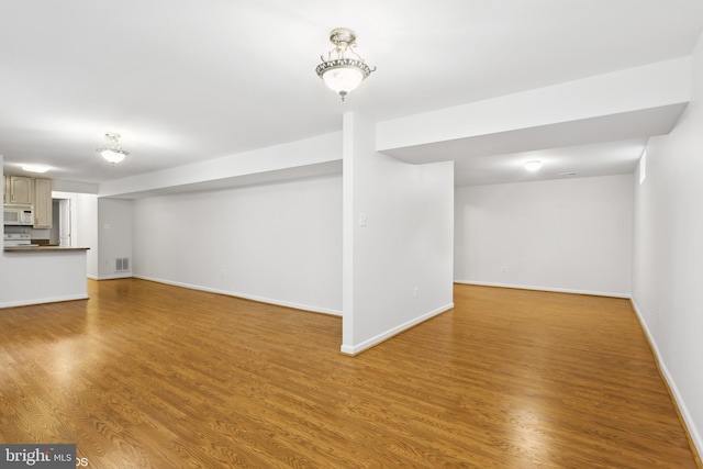 unfurnished living room with wood finished floors, baseboards, and visible vents