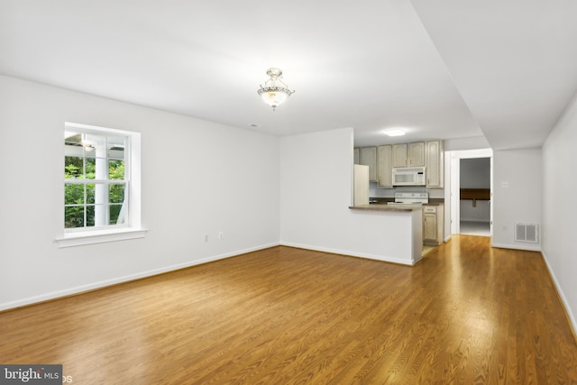 unfurnished living room with baseboards, visible vents, and wood finished floors