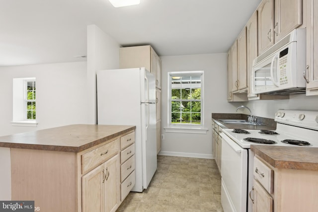 kitchen with light brown cabinets, a sink, dark countertops, and white appliances
