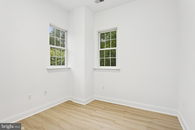 unfurnished room with baseboards, visible vents, and light wood-type flooring