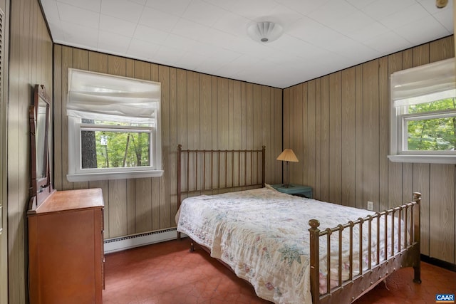 bedroom featuring multiple windows, wood walls, and a baseboard radiator