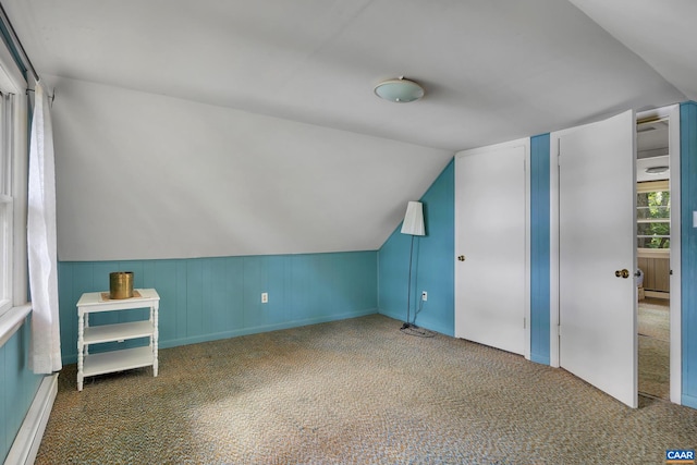 bonus room featuring lofted ceiling, dark colored carpet, and a baseboard heating unit