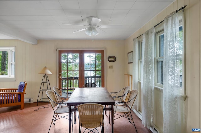 dining room featuring beam ceiling, wooden walls, baseboard heating, and ceiling fan