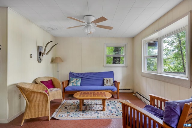 living room featuring wood walls, ceiling fan, and a baseboard radiator