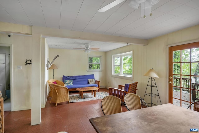 dining space with a baseboard radiator, beam ceiling, ceiling fan, and wood walls