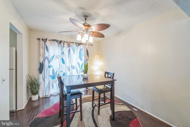 dining area with ceiling fan, dark hardwood / wood-style floors, and a textured ceiling