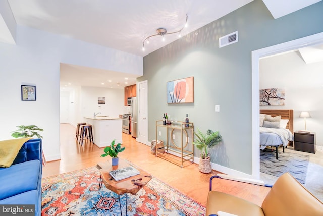 living room with rail lighting and light hardwood / wood-style floors