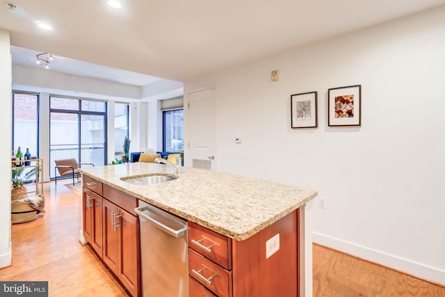 kitchen featuring light hardwood / wood-style floors, a center island with sink, light stone counters, dishwasher, and sink