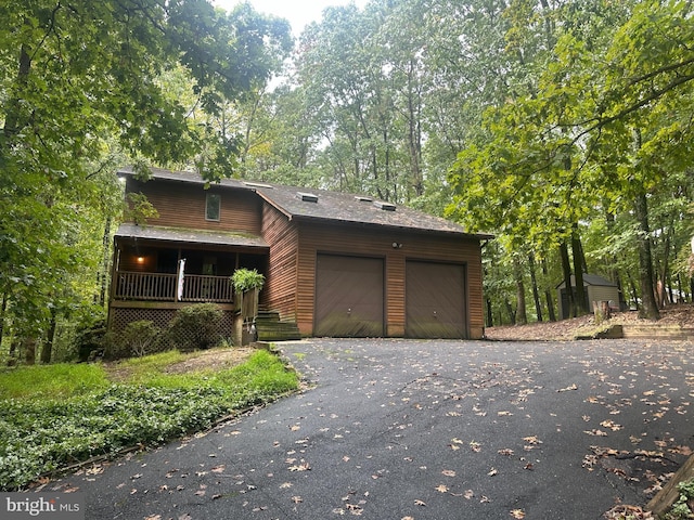 chalet / cabin with driveway, covered porch, and an attached garage