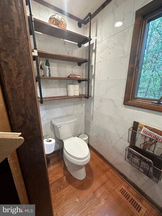 bathroom with visible vents, toilet, tile walls, and wood finished floors