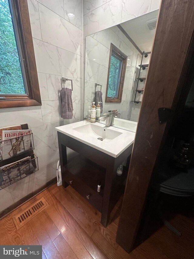 bathroom with vanity, tile walls, wood finished floors, and visible vents