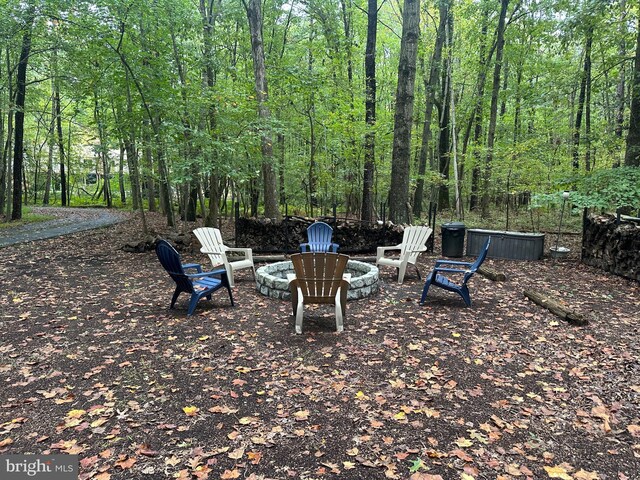 view of yard with a fire pit and a view of trees