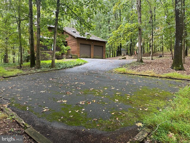 view of side of property with a wooded view and a detached garage