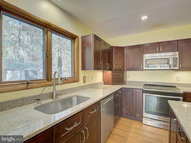 kitchen with light stone counters, light wood finished floors, recessed lighting, a sink, and appliances with stainless steel finishes