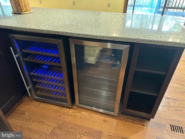 room details with visible vents, wine cooler, a bar, and light stone countertops