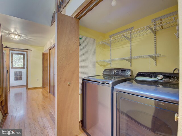 clothes washing area with laundry area, washer and dryer, light wood-type flooring, and baseboards