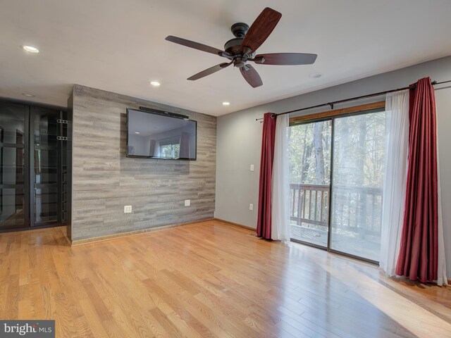 unfurnished living room with recessed lighting, wood finished floors, and an accent wall