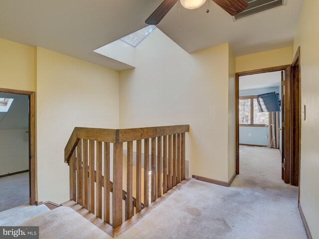 corridor featuring baseboards, carpet floors, and a skylight