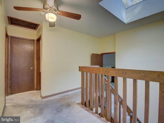 corridor with visible vents, an upstairs landing, a skylight, carpet flooring, and baseboards