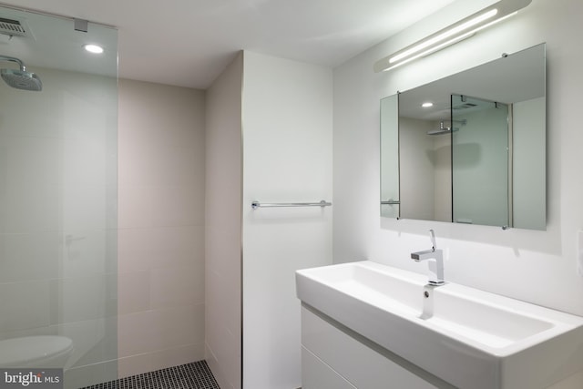 bathroom with vanity, a tile shower, toilet, and tile patterned floors