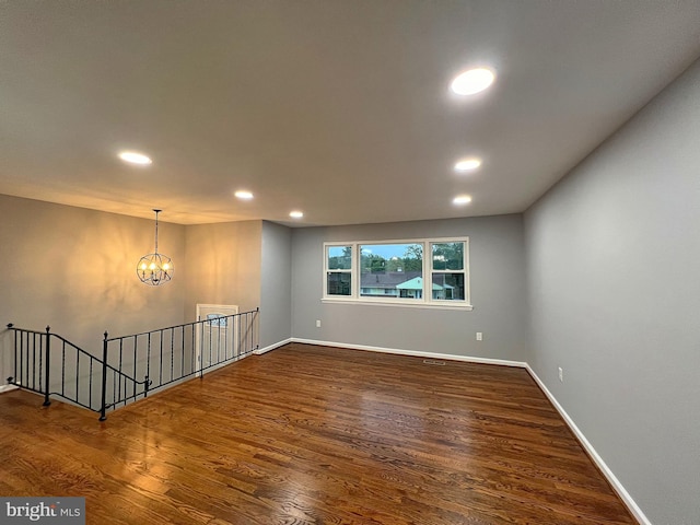 empty room with dark hardwood / wood-style floors and an inviting chandelier