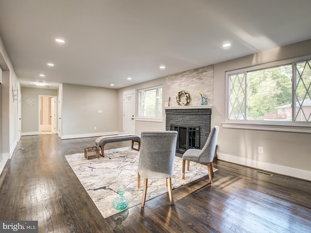 living room with a brick fireplace, plenty of natural light, and dark hardwood / wood-style flooring