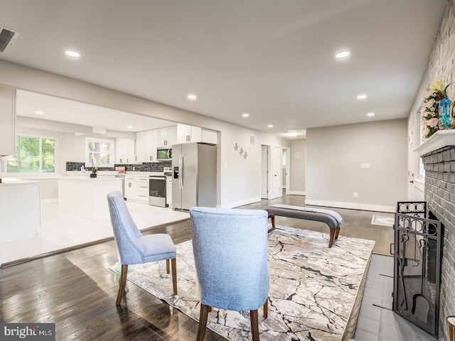 living room featuring a brick fireplace, light hardwood / wood-style floors, and sink