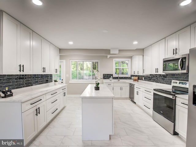 kitchen with stainless steel appliances, a center island, decorative backsplash, and white cabinetry