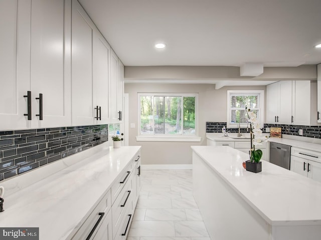 kitchen with decorative backsplash, dishwasher, sink, and white cabinets