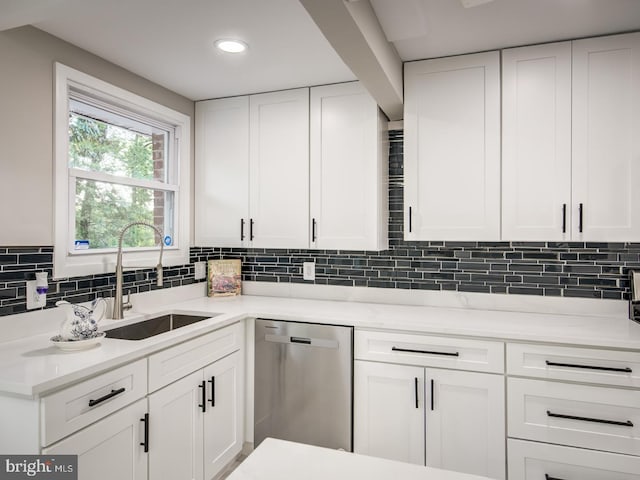 kitchen with decorative backsplash, white cabinets, dishwasher, and sink