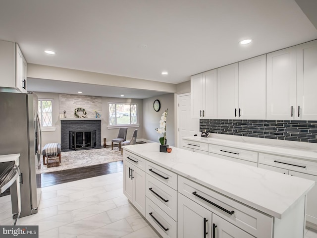 kitchen featuring a brick fireplace, light hardwood / wood-style flooring, plenty of natural light, and white cabinetry