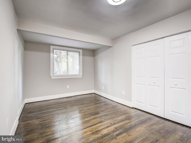 unfurnished bedroom featuring dark wood-type flooring and a closet