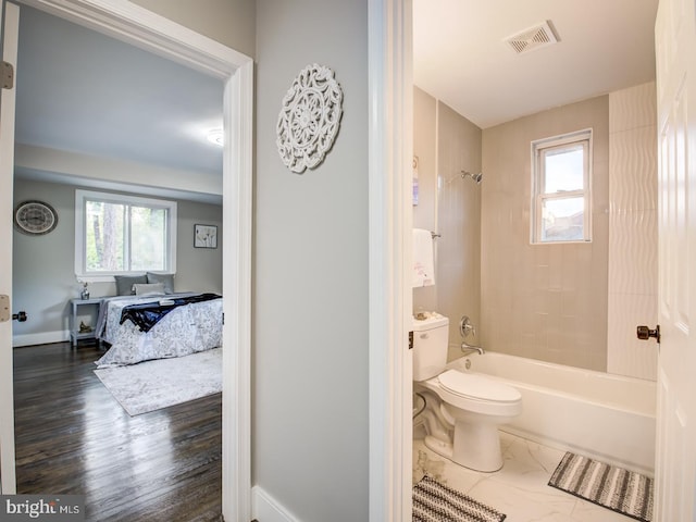 bathroom featuring hardwood / wood-style flooring, plenty of natural light, tiled shower / bath, and toilet