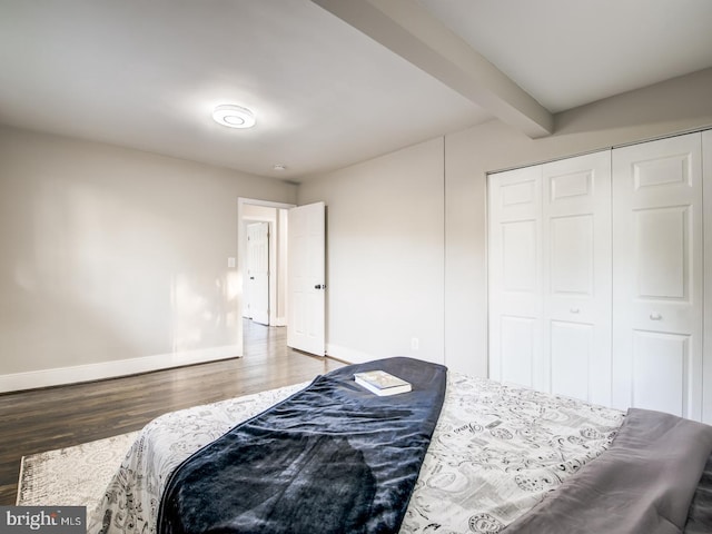 bedroom with beam ceiling, a closet, and dark wood-type flooring