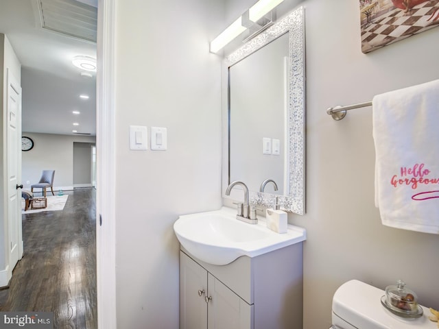 bathroom with wood-type flooring, vanity, and toilet