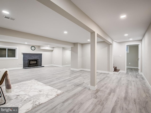 basement with a fireplace and light hardwood / wood-style floors