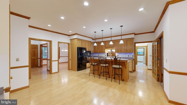 kitchen featuring pendant lighting, a kitchen island, a breakfast bar, light wood-type flooring, and black refrigerator