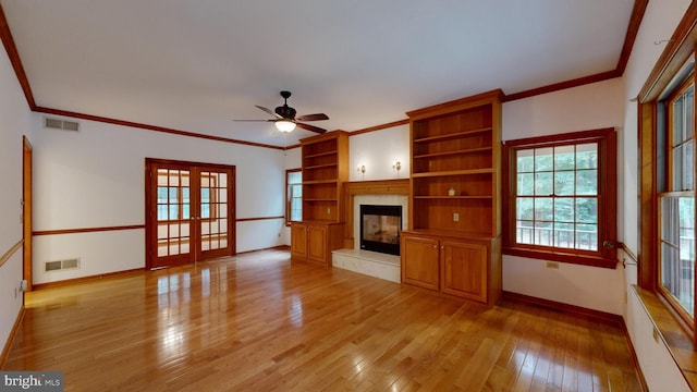 unfurnished living room featuring ceiling fan, light wood-type flooring, ornamental molding, and a high end fireplace