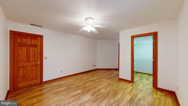 unfurnished bedroom featuring a spacious closet, ceiling fan, a closet, and light hardwood / wood-style flooring