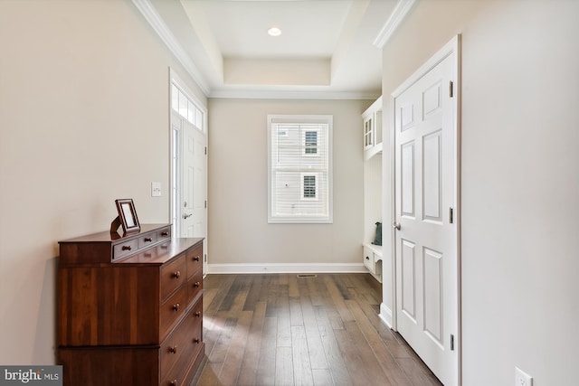 doorway with a tray ceiling, crown molding, and dark wood-type flooring