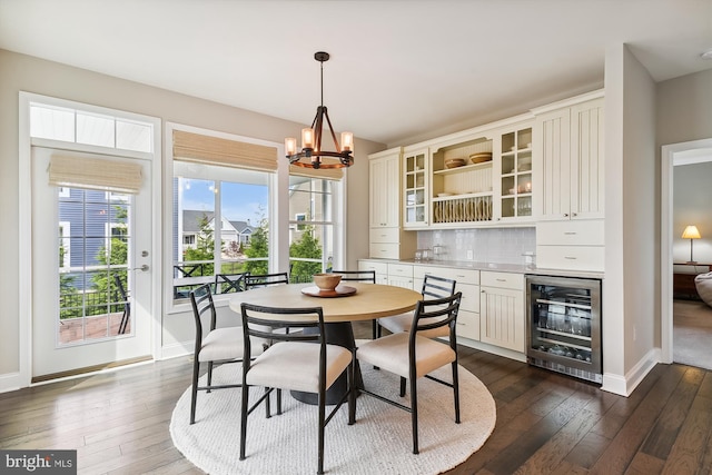 dining area with dark wood-type flooring, wine cooler, and an inviting chandelier