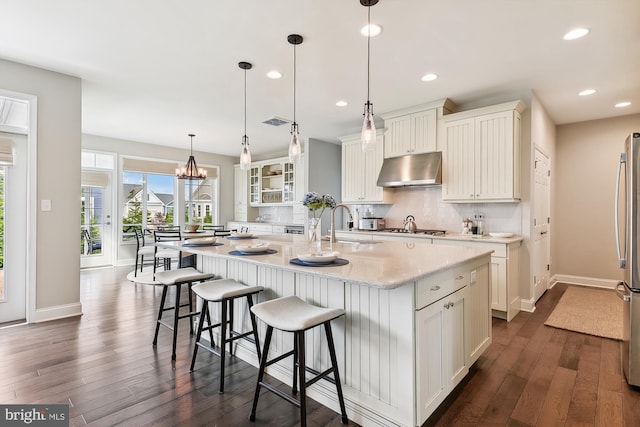 kitchen featuring an island with sink, dark hardwood / wood-style flooring, white cabinetry, and tasteful backsplash