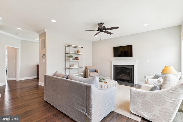 living room featuring ornamental molding, a fireplace, ceiling fan, and dark hardwood / wood-style floors