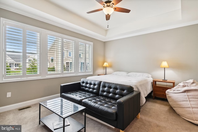 carpeted bedroom with crown molding, a tray ceiling, and ceiling fan