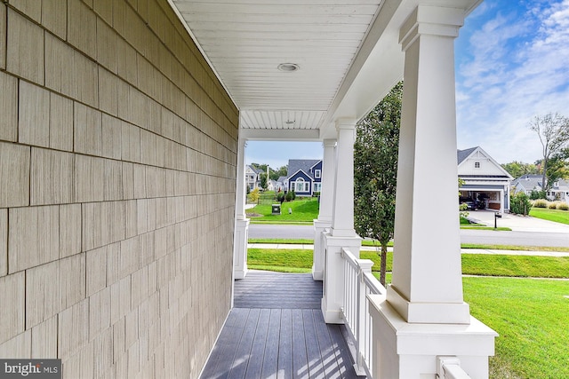 wooden terrace featuring a yard, covered porch, and a garage