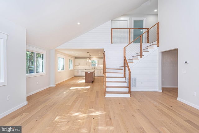 unfurnished living room featuring a high ceiling, light hardwood / wood-style floors, and wood walls