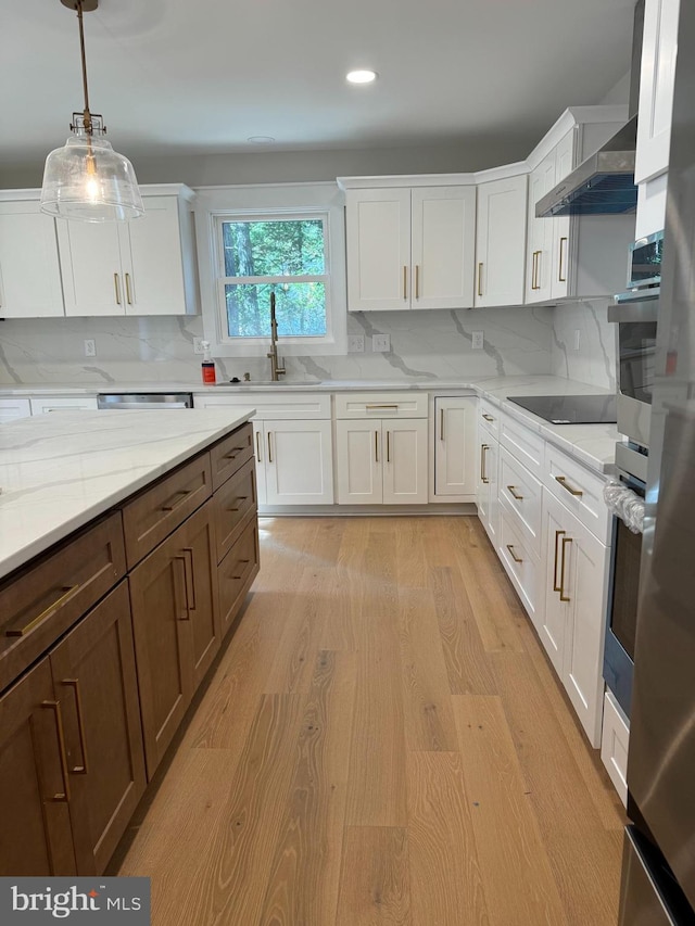 kitchen with black electric stovetop, white cabinetry, light hardwood / wood-style flooring, and decorative light fixtures