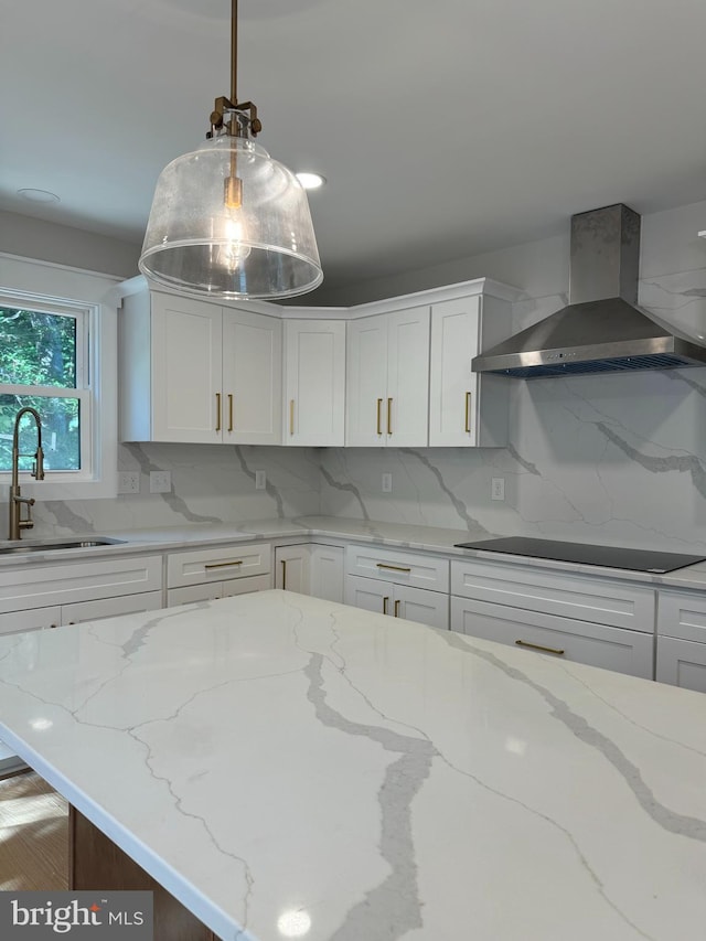 kitchen featuring wall chimney range hood, sink, black electric cooktop, and white cabinets