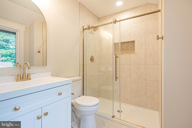 bathroom with a shower with door, vanity, and toilet